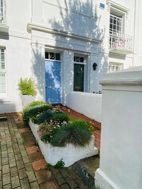 A small, well-maintained front garden area outside a white residential building with the number 78 displayed near a dark green door. The garden features a raised white concrete border containing a var